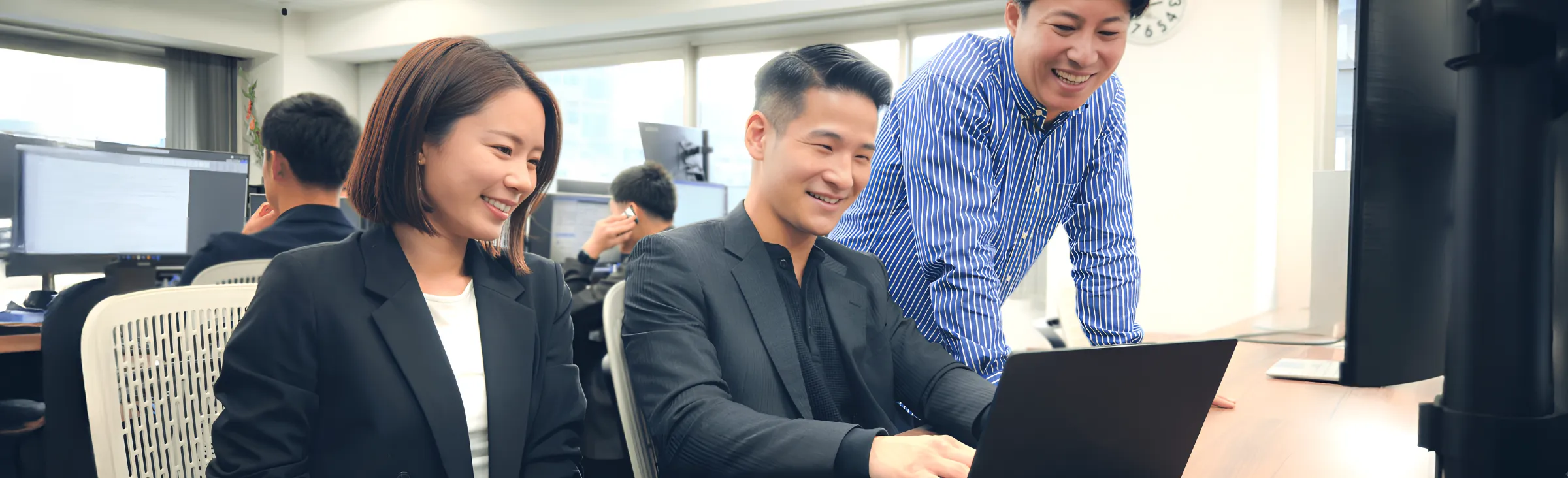 PC見ながら会話する社員3人